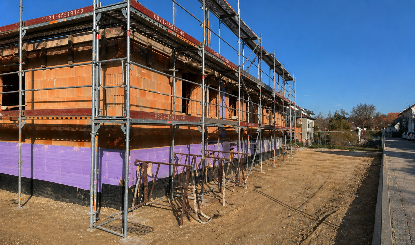 Rohbau des 3er Reihenhauses in Erding mit Gerüst, weit fortgeschrittener Baukörper kurz vor Fertigstellung des Rohbaus.